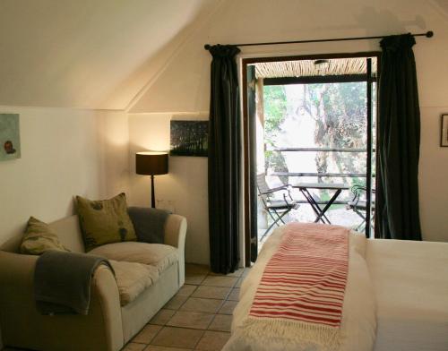 ein Wohnzimmer mit einem Sofa und einem Fenster in der Unterkunft Porcupine Hills Olive and Guest Farm in Botrivier