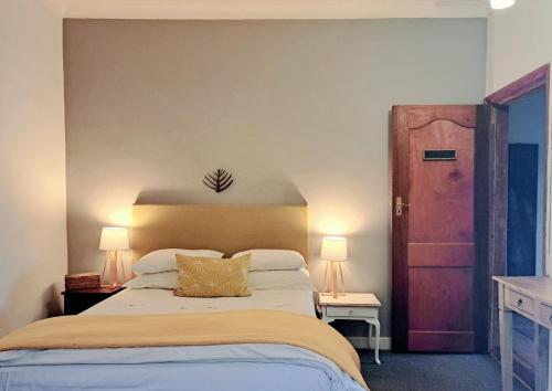 a bedroom with a bed and two lamps and a door at Porcupine Hills Olive and Guest Farm in Botrivier