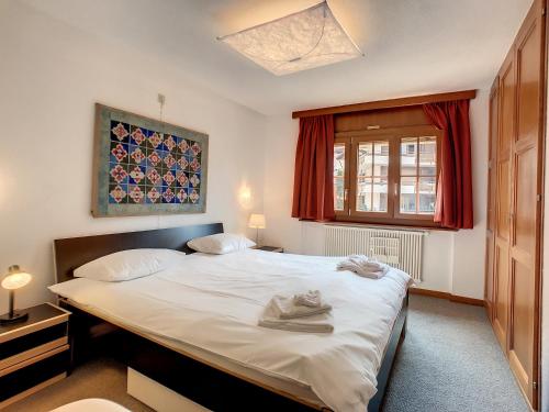 a bedroom with a large white bed with red curtains at Apartment Jacky 7 in Verbier