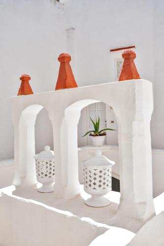 a white arch with three vases and a plant in it at Relais Corte Palmieri & Il Chiostro - Residenza d'epoca in Gallipoli
