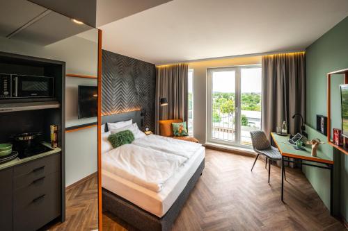 Schlafzimmer mit einem Bett, einem Schreibtisch und einem Fenster in der Unterkunft LOGINN Hotel Berlin Airport in Berlin