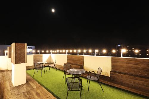 a group of tables and chairs on a balcony at night at Cornerstone Hotel in Seogwipo