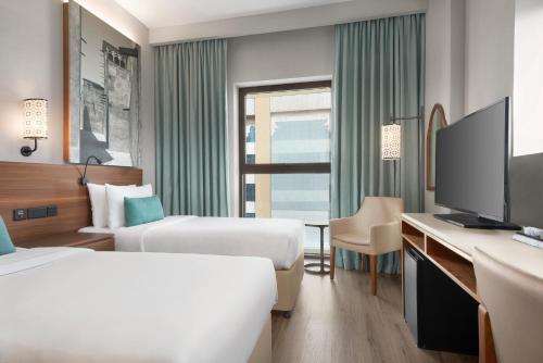 a hotel room with two beds and a desk with a tv at ibis Styles Dubai Gold District in Dubai
