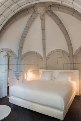 a large white bed in a room with arched ceilings at SOZO Hotel in Nantes
