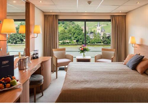 KD Hotelship Düsseldorf Comfort Plus في دوسلدورف: غرفة في الفندق مع سرير ومكتب مع كراسي