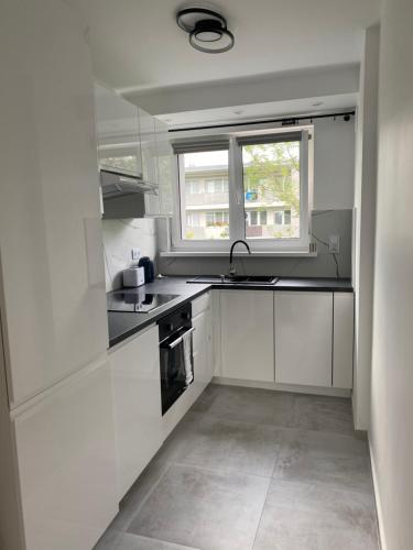 a white kitchen with a sink and a window at Apartament Malczewskiego in Kłodzko
