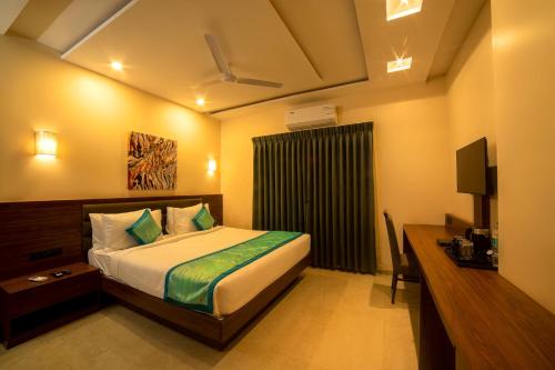 Dormitorio con cama, escritorio y TV en The Bliss Hotel en Hubli