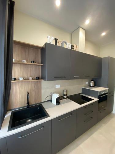 a kitchen with gray cabinets and a sink at Levante apartment and room in Bari