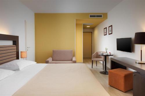 a hotel room with a bed and a desk and a chair at Hotel Garden Istra Plava Laguna in Umag