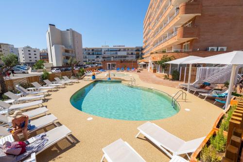 Una piscina con tumbonas y un edificio. en Prestige Sant Marc, en Roses