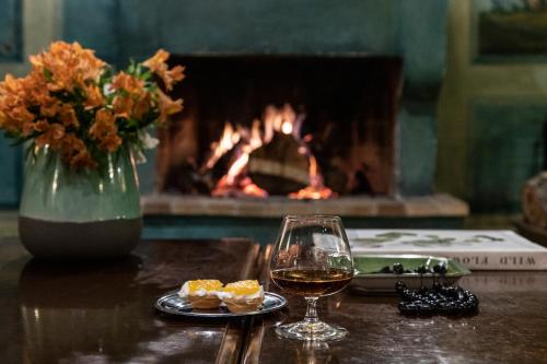 a glass of wine on a table with a fireplace at Amalia Hotel Meteora in Kalabaka