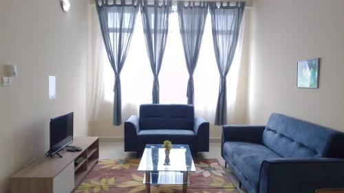 - un salon avec deux canapés bleus et une télévision dans l'établissement VUE RESIDENCES SERVICE SUITE 8 Pax, à Kuala Lumpur