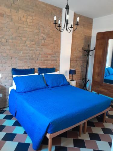 un letto blu in una stanza con muro di mattoni di Ventisette a Cremona