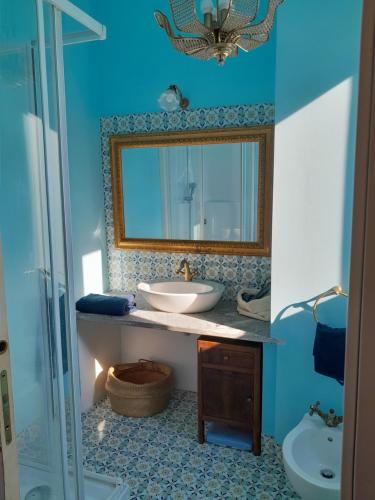 a blue bathroom with a sink and a mirror at Ventisette in Cremona