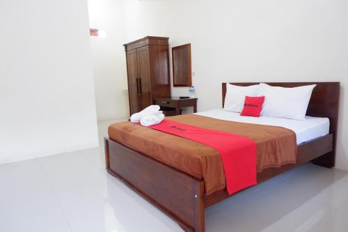 a bedroom with a bed with a red blanket at Reddoorz at Bale Eja Syariah Senggigi in Montongbuwoh
