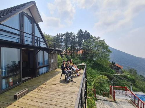 a group of people sitting on the deck of a house at Ban Mai Xanh homestay Tam Đảo in Vĩnh Phúc