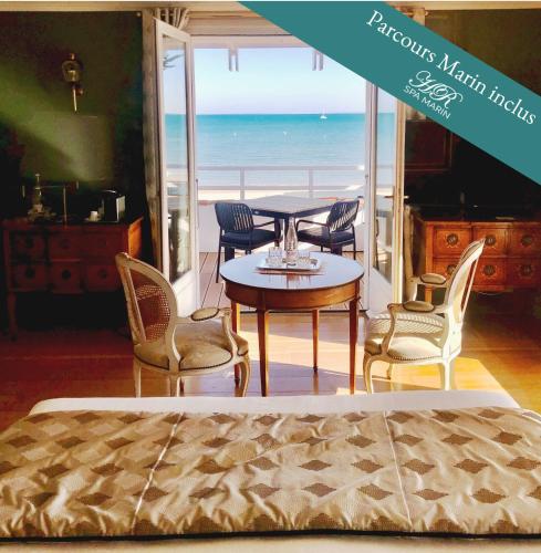 une chambre avec une table et des chaises et l'océan dans l'établissement HR Hôtel-Restaurant & Spa Marin, à La Flotte