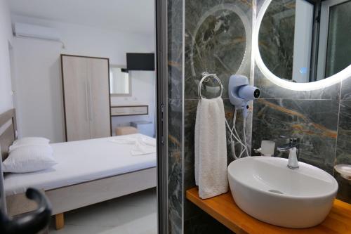 a bathroom with a sink and a bed and a mirror at Hotel Joni Lukove in Lukovë