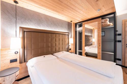 ein großes weißes Bett in einem Zimmer mit Holzdecken in der Unterkunft Garnì Letizia in Campitello di Fassa