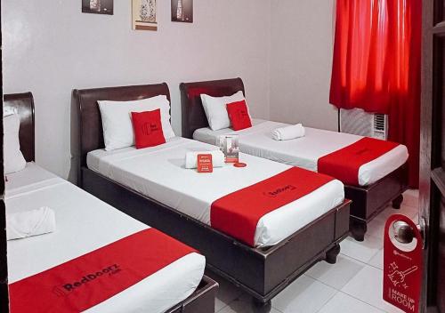 two beds with red and white sheets in a room at RedDoorz near Ormoc Port Terminal in Ormoc