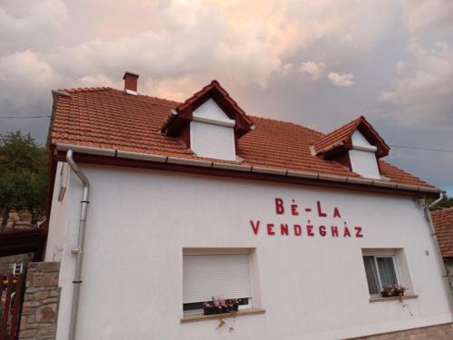 a white house with a red roof and the words be la verbia at Bé-La Vendégház in Szomolya