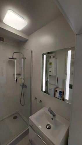 a bathroom with a sink and a shower and a mirror at Apartamenty Baltic Korona B19 in Darłowo