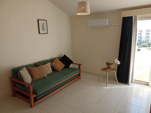 a living room with a green couch and a window at Mandalena Hotel Apartments in Protaras