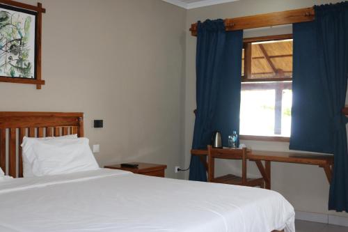 a bedroom with a bed and a window with blue curtains at Pescador Villas in Inhambane