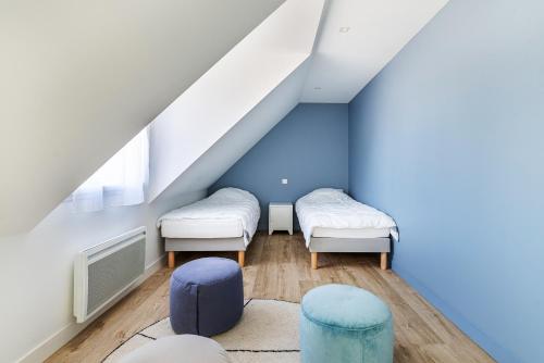 Cette chambre comprend 2 lits et un mur bleu. dans l'établissement Les Peupliers - maison de vacances avec jardin, à Bénodet