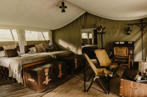a bedroom with a bed and a desk and a chair at Serengeti Pioneer Camp in Mugumu