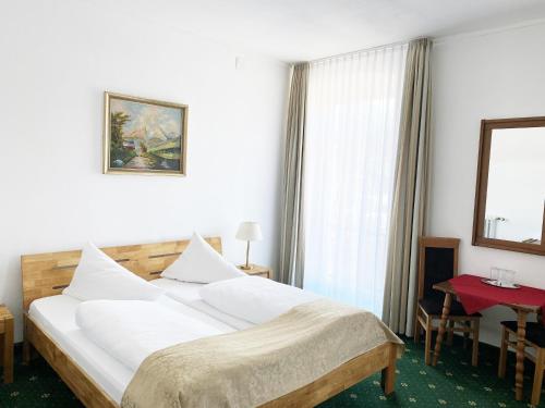 a bedroom with a large white bed and a red table at Hotel Schwabenwirt in Berchtesgaden