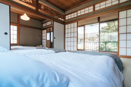 eine Reihe weißer Betten in einem Zimmer mit Fenstern in der Unterkunft mysa hakone in Hakone
