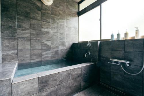 a bathroom with a shower with a tub and a window at mysa hakone in Hakone