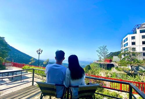 a man and woman sitting on a bench looking at the view at Ban Mai Xanh homestay Tam Đảo in Vĩnh Phúc