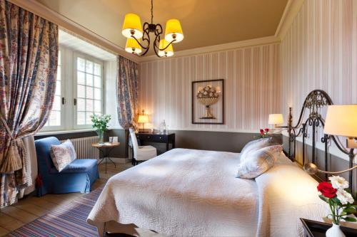 a bedroom with a bed and a blue chair at Chateau De Germigney in Port-Lesney