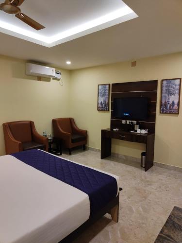 a hotel room with a bed and a tv and chairs at Eshanya Comforts in Attibele