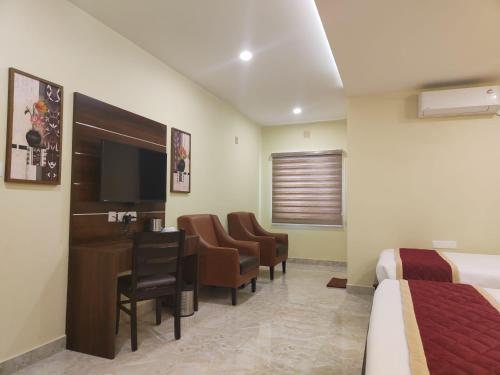 a hotel room with a bed and a desk and chairs at Eshanya Comforts in Attibele