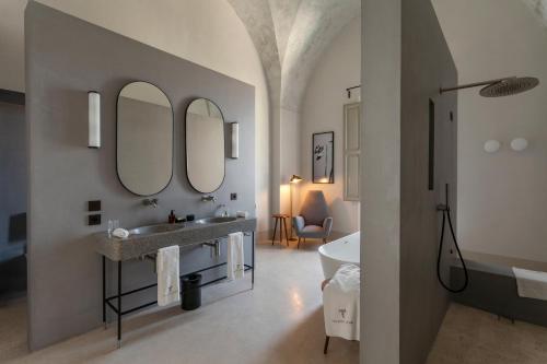 La salle de bains est pourvue de 2 miroirs, d'un lavabo et d'une baignoire. dans l'établissement Palazzo Tafuri, à Nardò