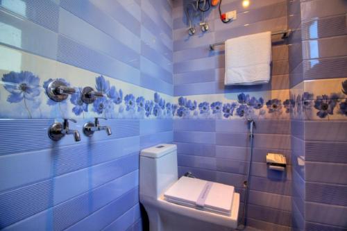 a blue tiled bathroom with a toilet and towels at Ark of Avalon Near IGI AirPort New Delhi in New Delhi