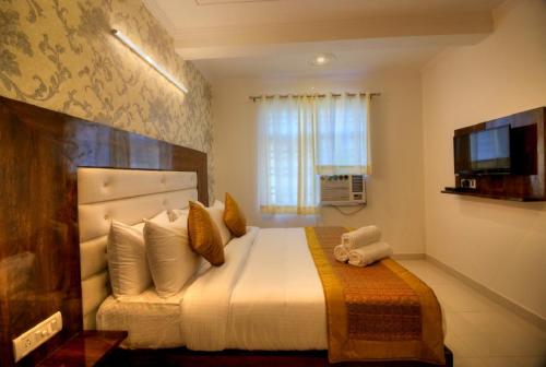 a bedroom with a large bed and a television at Ark of Avalon Near IGI AirPort New Delhi in New Delhi
