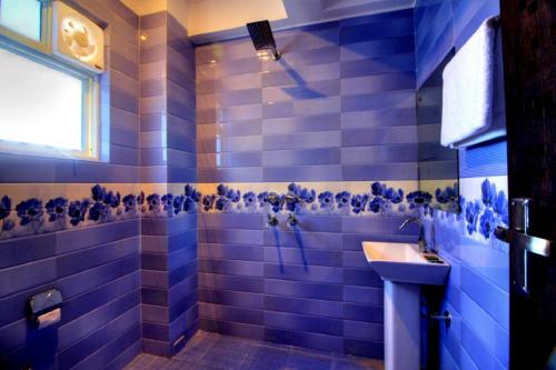 a blue tiled bathroom with a sink and a shower at Ark of Avalon DEL - FREE Airport Drop in New Delhi
