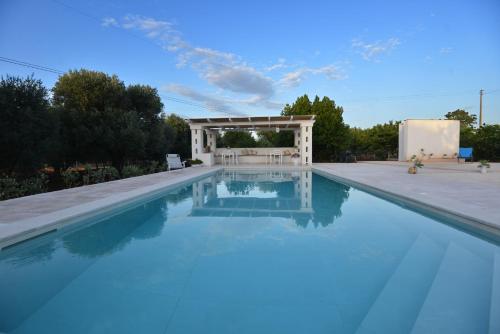 een zwembad met een tuinhuisje op de achtergrond bij Villa del Sole in Ostuni