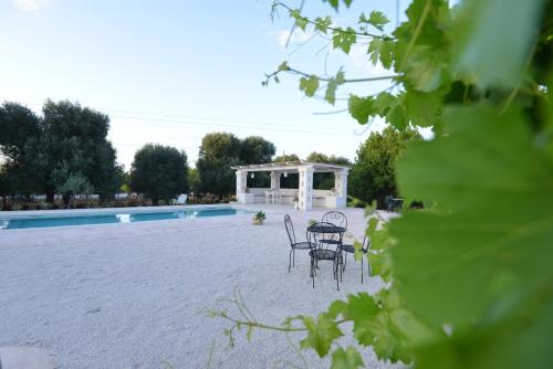 een patio met tafels en stoelen naast een zwembad bij Villa del Sole in Ostuni