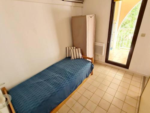 1 dormitorio con 1 cama azul en una habitación con ventana en Appartement Six-Fours-les-Plages, 2 pièces, 4 personnes - FR-1-316-21, en Six-Fours-les-Plages