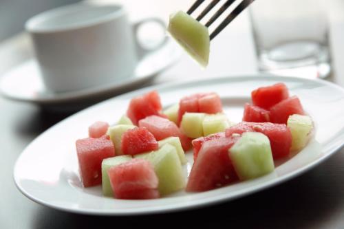 a plate of fruit on a table with a fork at Amaris Hotel Teuku Umar in Denpasar
