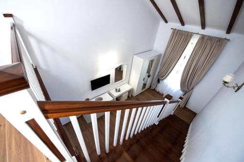 - un escalier dans une maison dotée de murs blancs et de parquet dans l'établissement Hanul Marioarei, à Roman