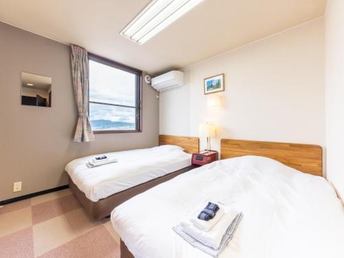 2 camas en una habitación con ventana en Tabist Travel Inn Shinshu Nakano, en Nakano