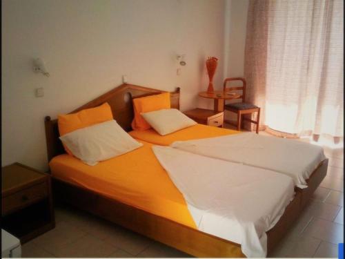 a bedroom with two beds with orange and white sheets at Room in Studio - Rock Garden Apartment by the beach in Pefki