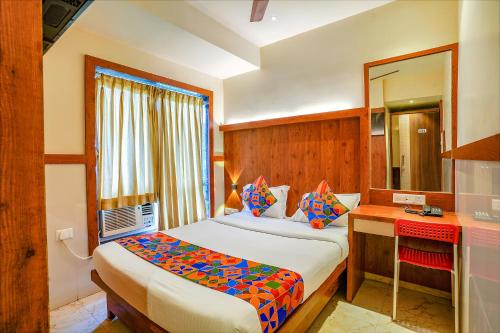 um quarto com uma cama, uma secretária e um espelho em FabExpress Super 7 Inn em Mumbai