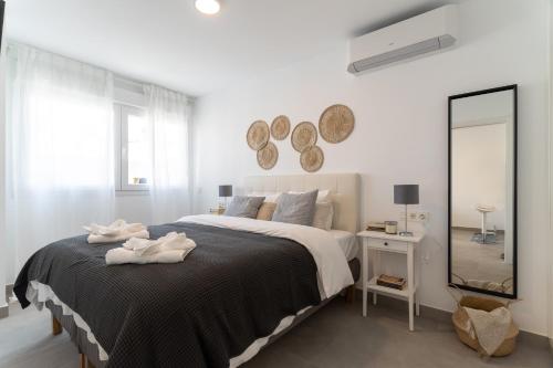 ein weißes Schlafzimmer mit einem großen Bett und einem Spiegel in der Unterkunft Cala Luxo en Cala de Mijas a metros del mar in Mijas Costa